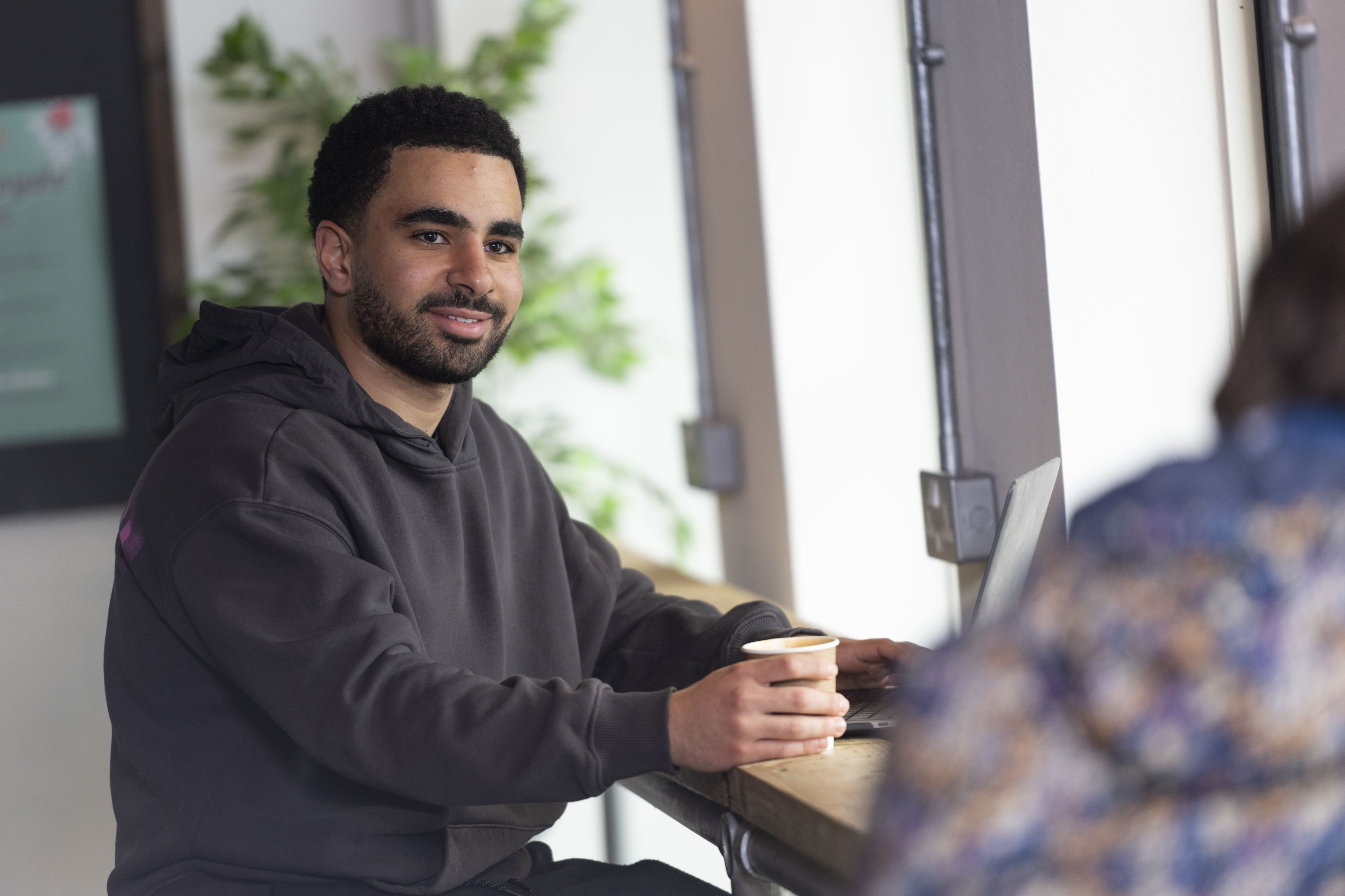 A student sits with a coffee in The Hideout